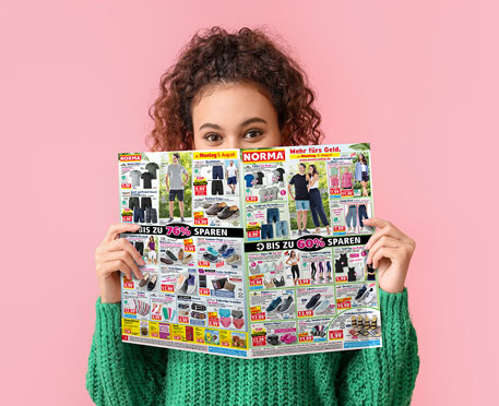 Eine Kundin blickt in einen NORMA Prospekt. Klicken Sie, um den für Sie gültigen Prospekt durch Auswahl einer Filiale zu bestimmen.